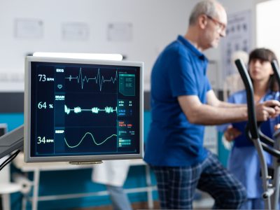 Close up of heart rate monitor measuring heartbeat for patient doing gymnastics for physical recovery. Retired man using sport equipment to exercise for physiotherapy and strength.